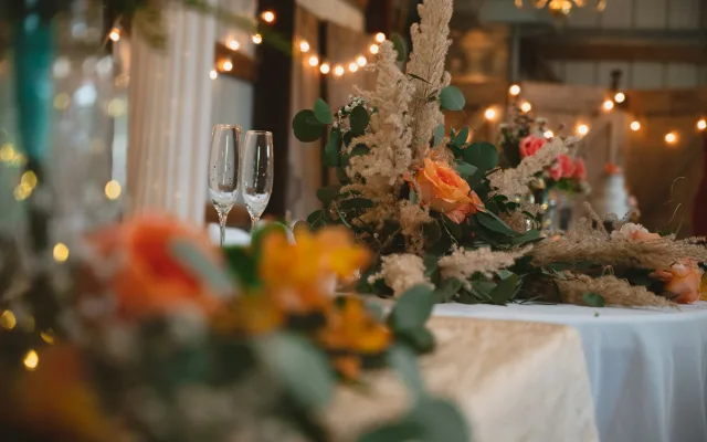 Fleurs d’automne et guirlandes lumineuses floues sur une table de réception de mariage
