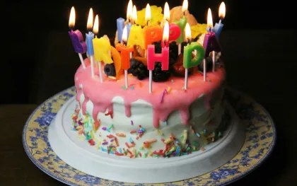 Gâteau d’anniversaire rose aux bougies colorées allumées